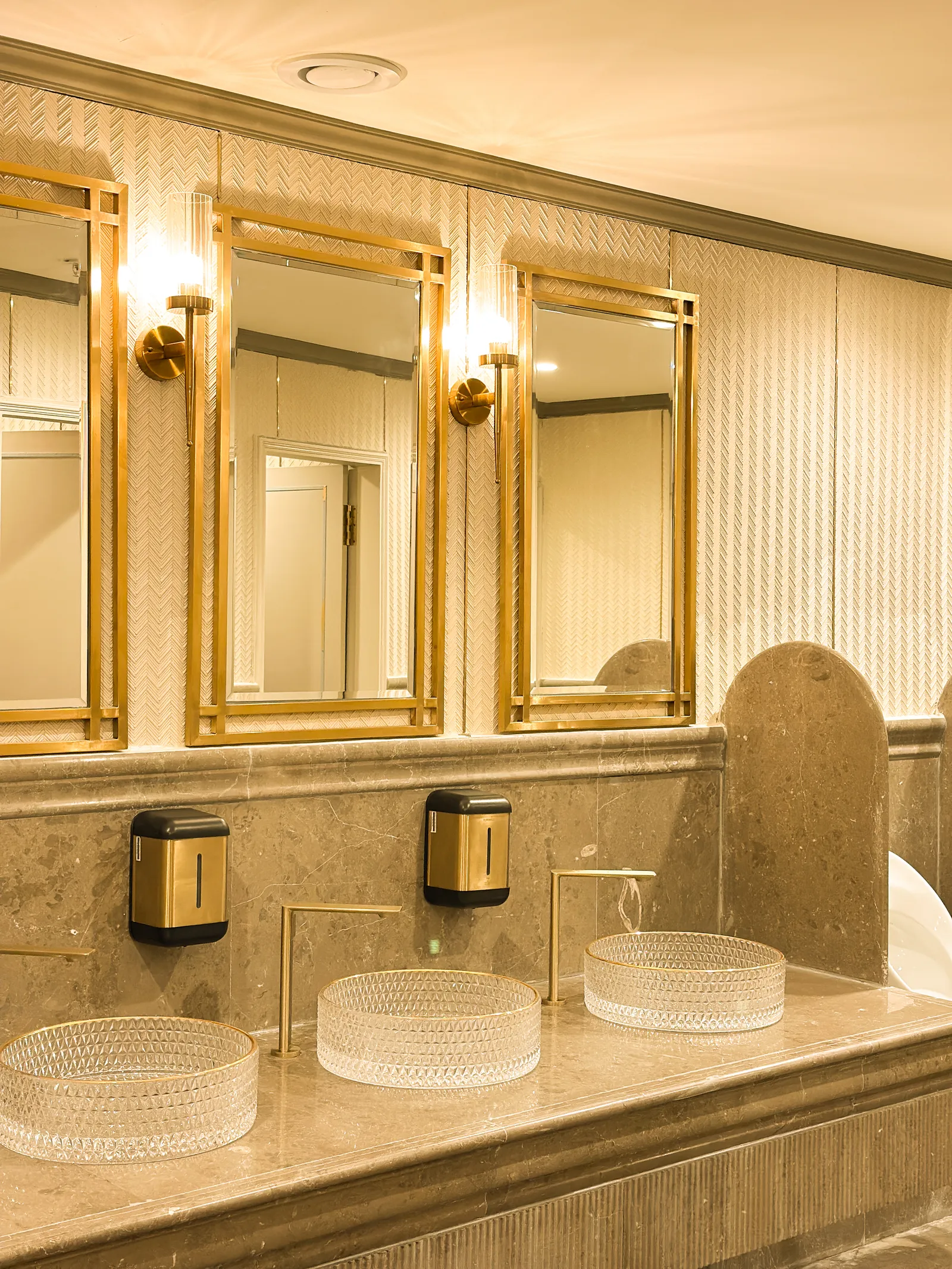 Restroom with brass mirrors and glass vessel basins — Chalukya Samrat